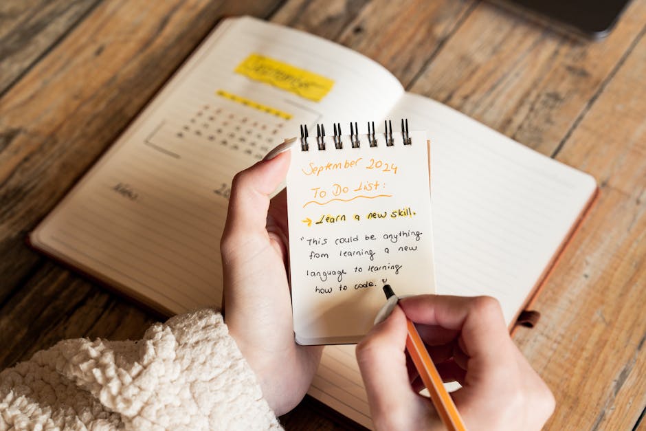 A person writes a September 2024 to-do list in a notebook, focusing on learning new skills.